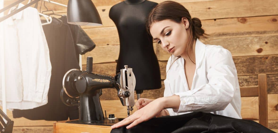 Seamstress working dark fabric through a sewing machine